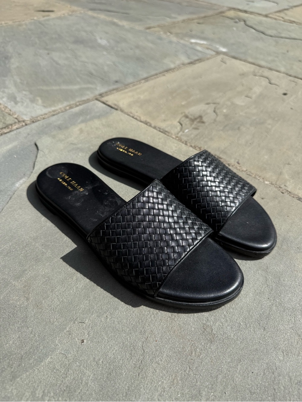 Cole Haan Analise Slide Sandals, featuring a distinct black woven leather upper.